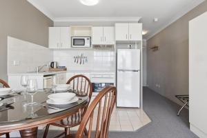 a kitchen with a table with chairs and a refrigerator at Horizons 302 in Jindabyne