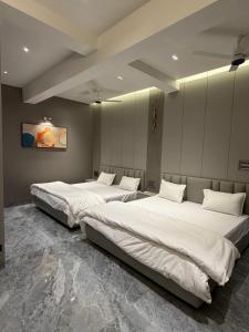 two beds in a room with white sheets at Exotica Stays in Alibaug