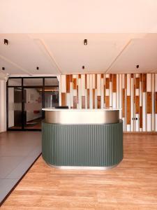 a lobby with a green counter and wooden floors at The Residence by Chakolas Pavilion in Cochin