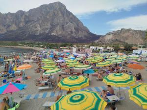 a bunch of people sitting on a beach with umbrellas at Marluna in Custonaci