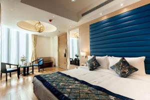a bedroom with a large bed with a blue wall at HOTEL SURYA GRAND in Siliguri