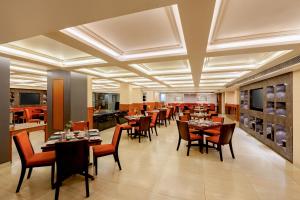 a restaurant with tables and chairs in a room at Classic Grande,a Member of Radisson in Imphal