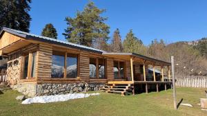 a log cabin with large windows in a yard at Heshkili huts and cabins Svaneti in Keshkili