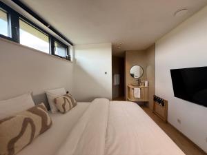 a bedroom with a large white bed and a flat screen tv at Wasserturm Hotel Elsenborn in Butgenbach