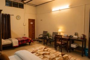 ein Zimmer mit einem Bett, einem Schreibtisch und einem Tisch in der Unterkunft Bononi in Jorhat