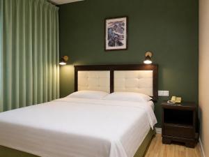 a bedroom with a large white bed and green walls at Mansion Inn Sibu in Sibu