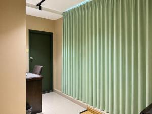 a room with green vertical blinds on the window at Mansion Inn Sibu in Sibu