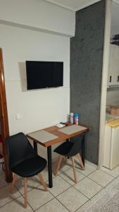 a table with two chairs and a television on a wall at Alesta Apartment in Tríkala