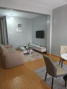 a living room with a couch and a tv at Zariah Homes 2BR in Kakamega