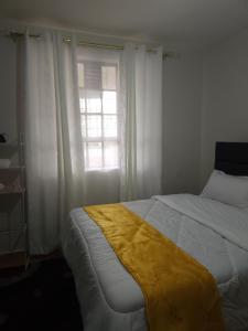 a bedroom with a bed with a yellow blanket on it at Zariah Homes 2BR in Kakamega