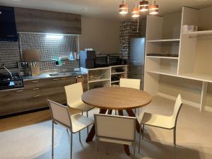 a kitchen with a wooden table and white chairs at ピンポンホテル Peace Park in Hiroshima