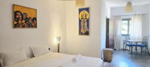 a bedroom with a bed and a table with chairs at Maison Carrée Andilana in Andilana