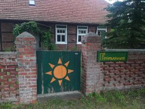 a green gate with a sun painted on it next to a brick building at Alte Schule Nausdorf in Lenzen