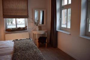 a bedroom with a bed and a table and windows at Stadtapartement Geisa in Geisa