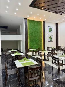 a restaurant with tables and chairs and a green wall at Hotel NASS del Sur in Cuenca