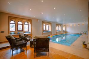 a large room with a pool with chairs and a table at Hotel Aurea Jaisalmer in Jaisalmer