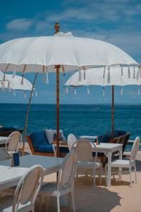 a white umbrella on the beach with chairs and tables at The Shacks at Sandy Bay in Nusa Lembongan