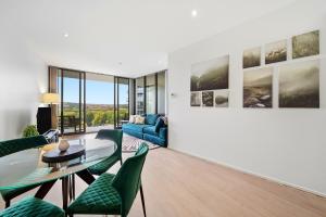 a living room with a glass table and green chairs at Stylish 1-Bed in CBD with Secure Underground Parking in Canberra