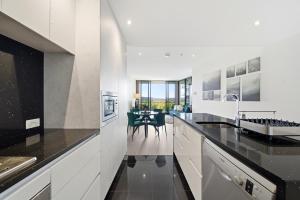 a kitchen with white cabinets and black counter tops at Stylish 1-Bed in CBD with Secure Underground Parking in Canberra +14 photos