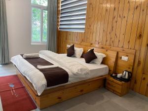 a large bed in a room with wooden walls at BlueWave Villa in Kangra +79 photos