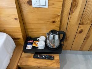 a tray with a tea kettle and cups on a bed at BlueWave Villa in Kangra