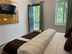 a large bed in a room with a television on the wall at BlueWave Villa in Kangra
