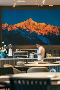 a man standing in a restaurant with a mountain mural at JOY Hotel Hangzhou in Hangzhou