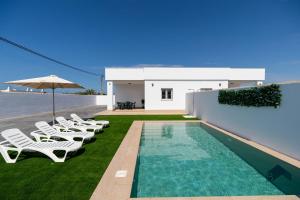 a villa with a swimming pool and lounge chairs at Ginebra B BARROSAHOME in Novo Sancti Petri