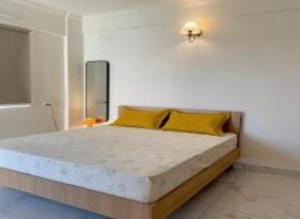 a bedroom with a large bed with yellow pillows at HomeSlice Sarjapur - Balcony Rooms in Bangalore
