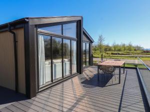 a house with a deck with a table and windows at Encil Gyfrinfa in Pwllheli