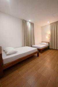 two beds in a room with wooden floors and curtains at Jon's Paradise Villa and Resto in Sajang