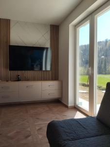 a living room with a flat screen tv on a wall at POČITNIŠKA HIŠA Jan in Mišji Dol