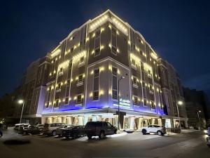 a lit up building with cars parked in a parking lot at Milestone Rise Jeddah in Jeddah