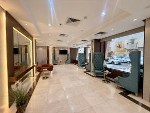 a waiting room with chairs and a table and a tv at Milestone Rise Jeddah in Jeddah