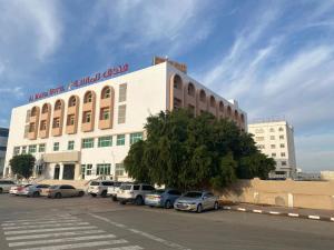 a large building with cars parked in a parking lot at Hotel Al Masa in Al Buraymī