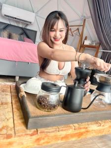 a woman is sitting at a table with a pot at เขาเจ้าขา-เต็นท์กระโจมเขาค้อ โดมvip in Khao Kho