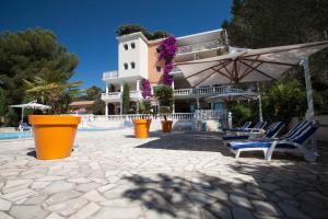 a building with chairs and an umbrella next to a pool at Appartement La Potinière in Saint-Raphaël