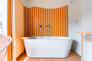 a bath tub in a bathroom with an orange wall at Nimman Bed at9 in Chiang Mai +36 photos