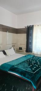 a bedroom with a bed with a green blanket on it at Cmt Lodge & Rooms in Mysore