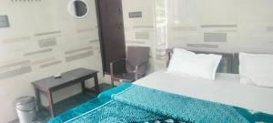 a bedroom with a bed and a table and a chair at Cmt Lodge & Rooms in Mysore