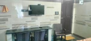 a room with a desk and a tv on a wall at Cmt Lodge & Rooms in Mysore