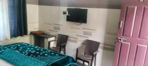 a room with a table and chairs and a tv on the wall at Cmt Lodge & Rooms in Mysore