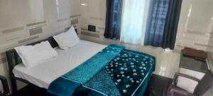 a bedroom with a bed with a green blanket on it at Cmt Lodge & Rooms in Mysore +1 photo