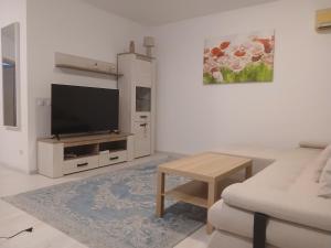 a white living room with a tv and a couch at Apart hotel Sara seaview in Olimp