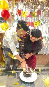 a man and a woman cutting a birthday cake at Hotel Mount View Inn with terrace Ganga view- near Laxman jhula, Tapovan Rishikesh in Rishīkesh