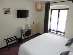 a bedroom with a bed and a desk and a window at Le Barriol in Saint-Julien-Chapteuil