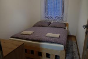a bedroom with a bed with two pillows and a window at Chatka pod Stinskou in Zboj
