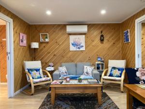 a living room with a couch and two chairs at Winganah Cottage in Murdunna