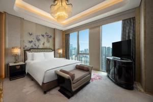 a bedroom with a large bed and a television at Wanda Reign Chengdu in Chengdu
