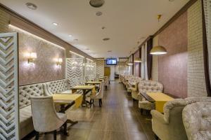 a restaurant with couches and tables and chairs at Elbrus Hotel in Cheboksary